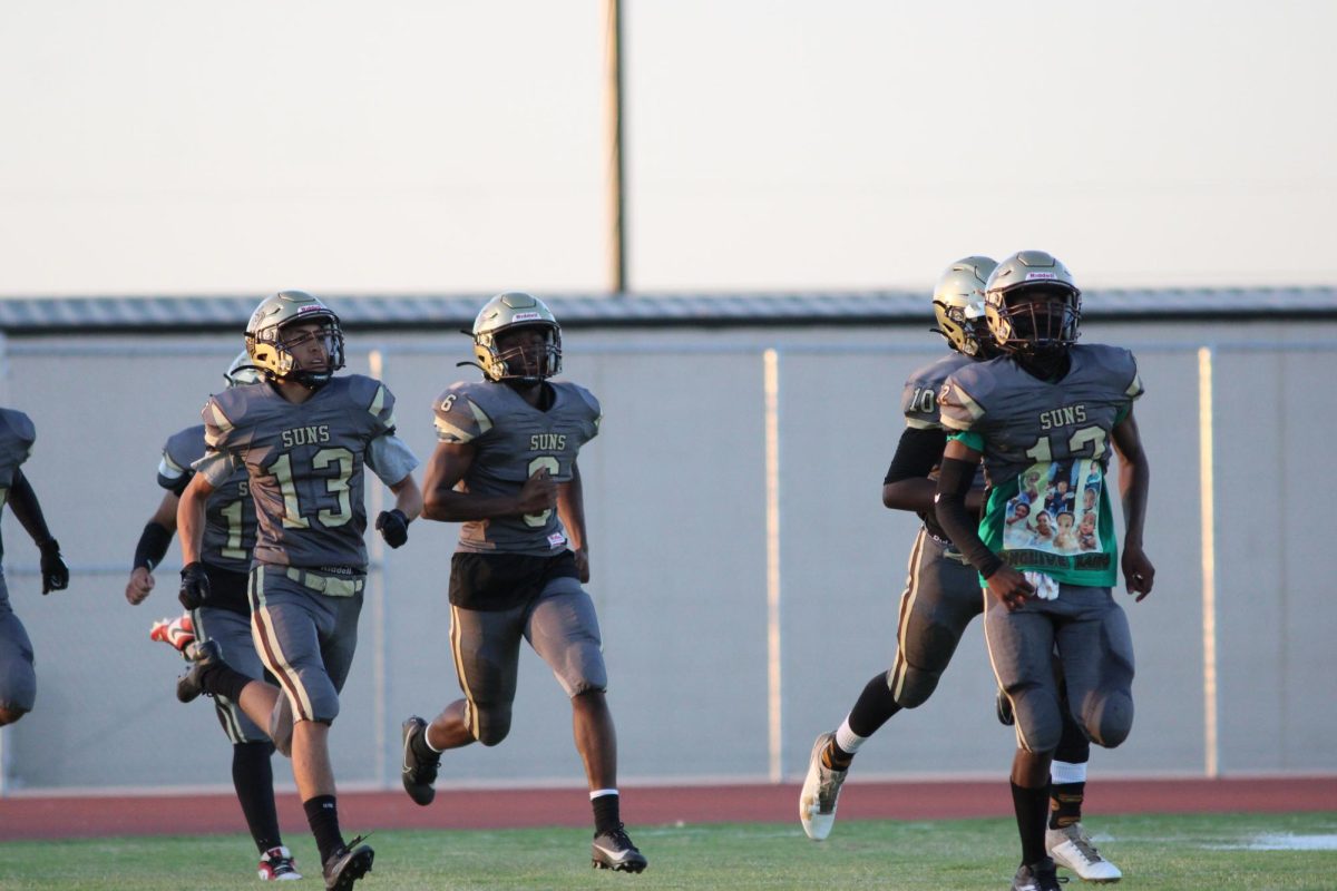 An emotional Ernest Jones IV (far right) leads the varsity squad onto the field, wearing a shirt under his jersey honoring his younger brother.