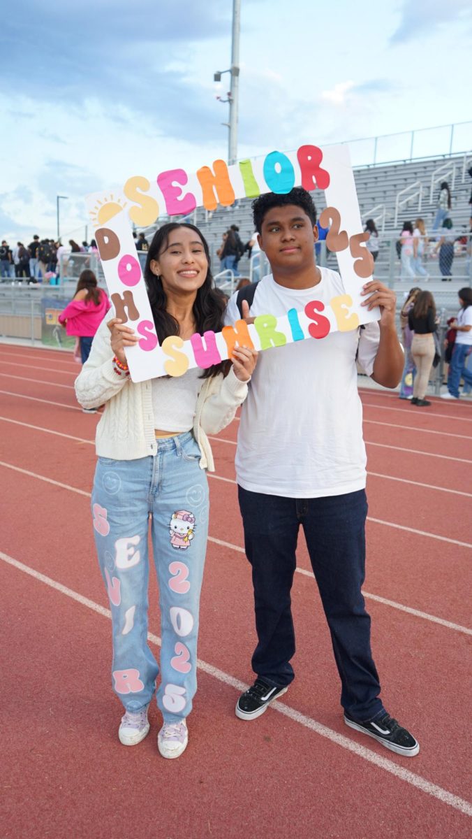 Alexa Cruz Rivera (left) and Davy Gomez pose behind a sign during Senior Sunrise on Sept. 20.