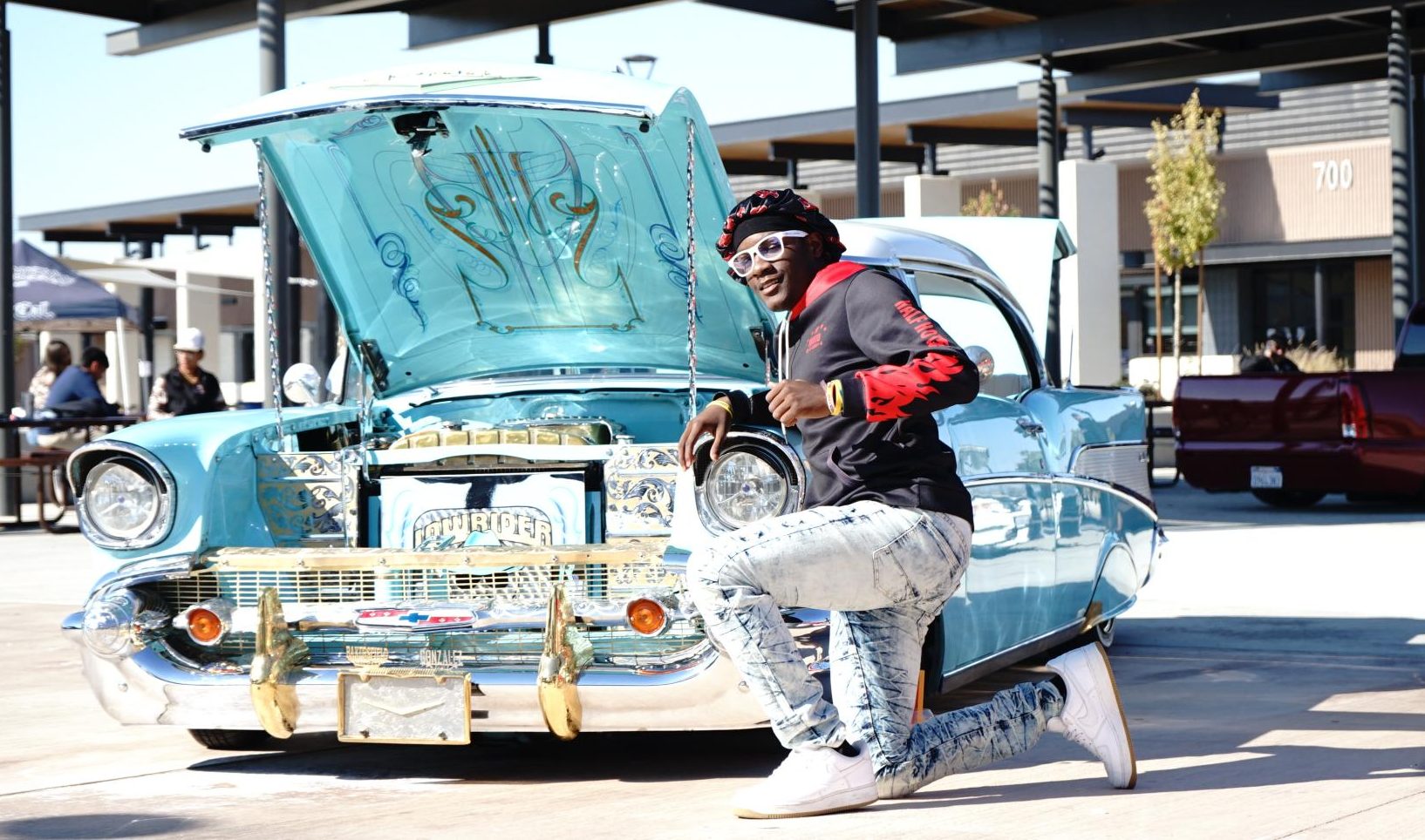 Junior Ernest Jones IV strikes a pose in front of a baby blue 1957 Chevrolet Bel Air owned by Junior Gonzalez of the Aztec Image car club.