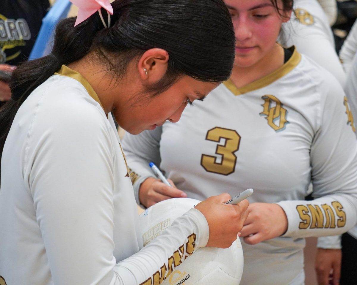 Lynneah Garza signs a game ball while sister Saraya looks on.