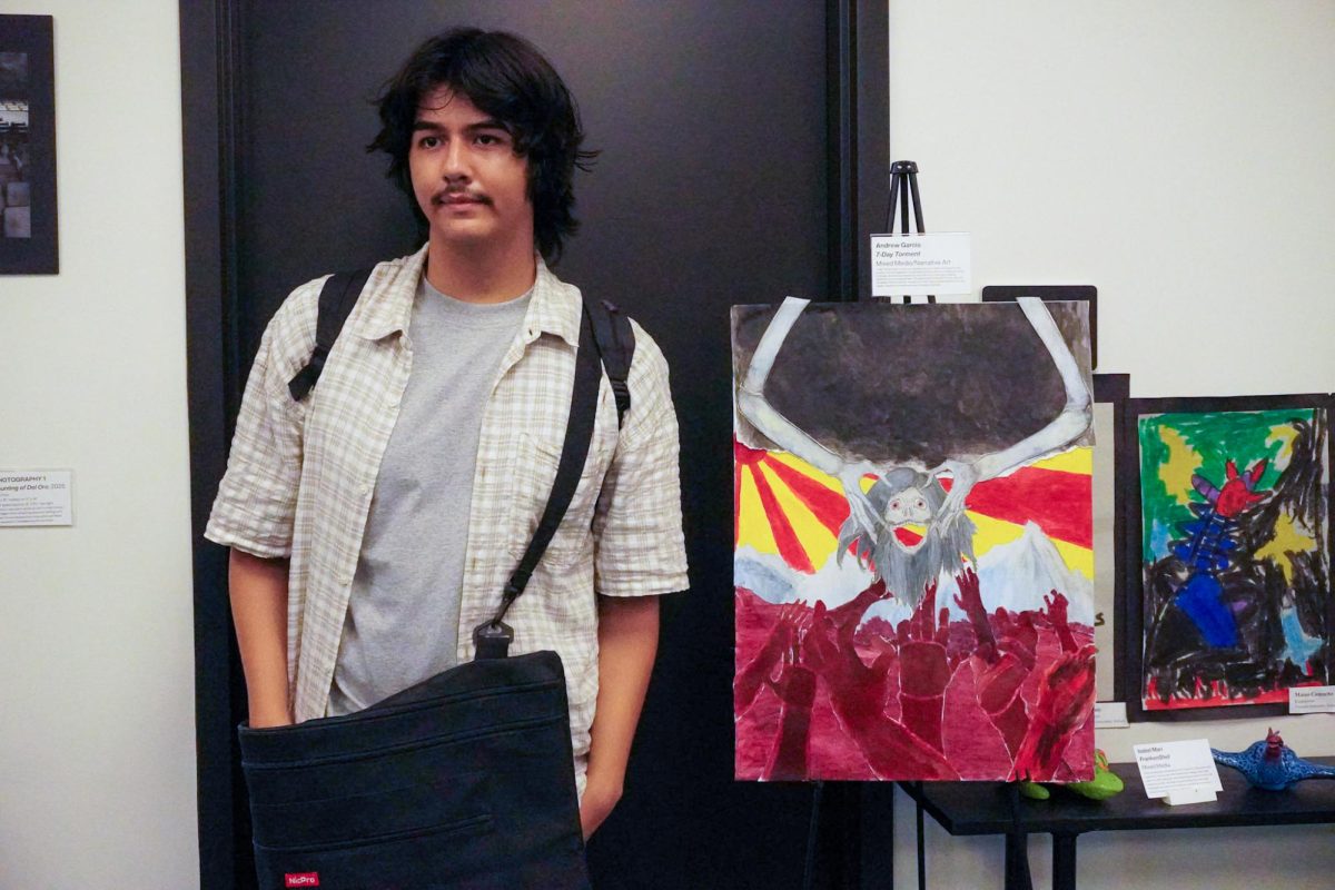 Andrew Garcia poses next a piece he submitted for the exhibit, titled "7-Day Torment."