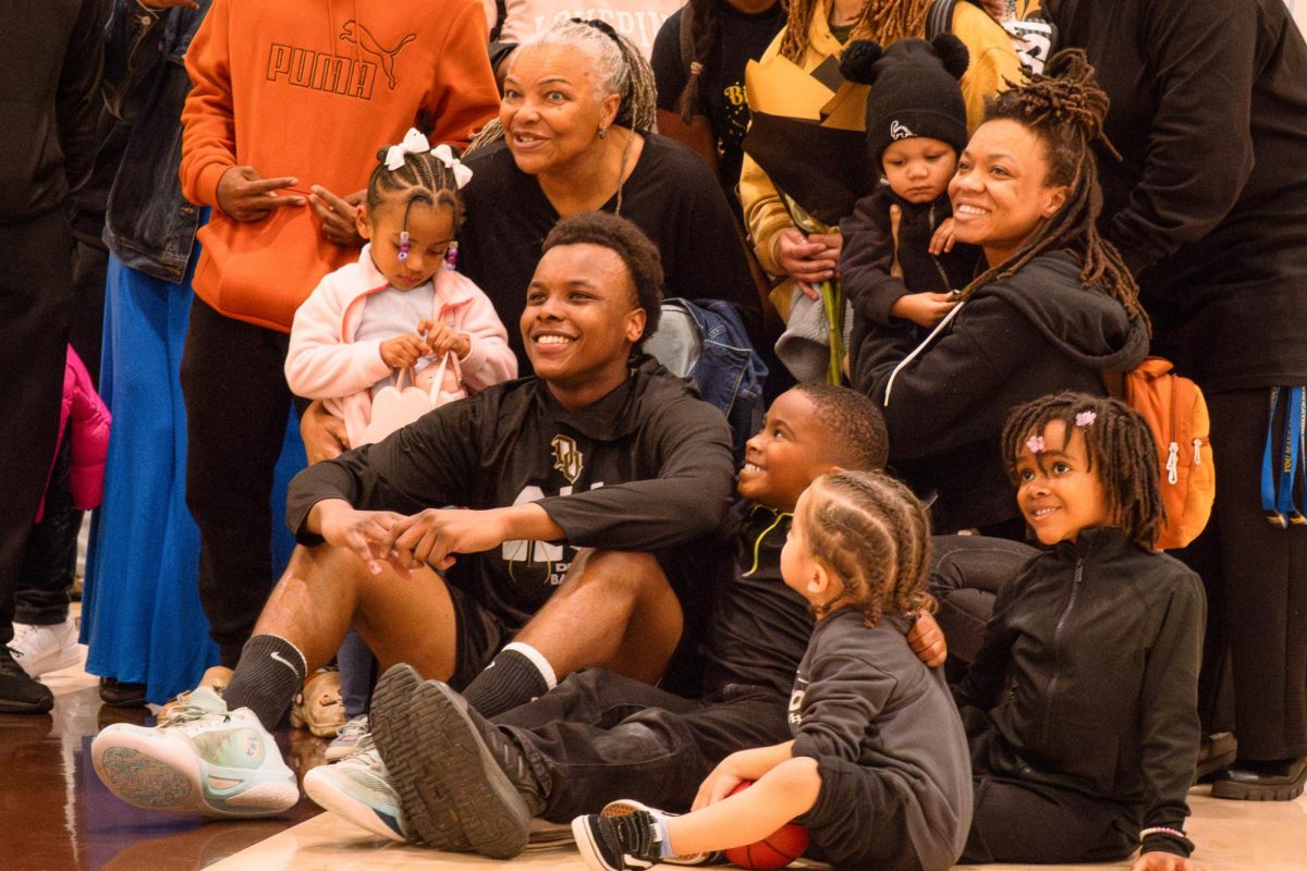 Senior point guard Keenan Starling smiles while surrounded by his family during boys basketball's senior night recognition ceremony on Tuesday.