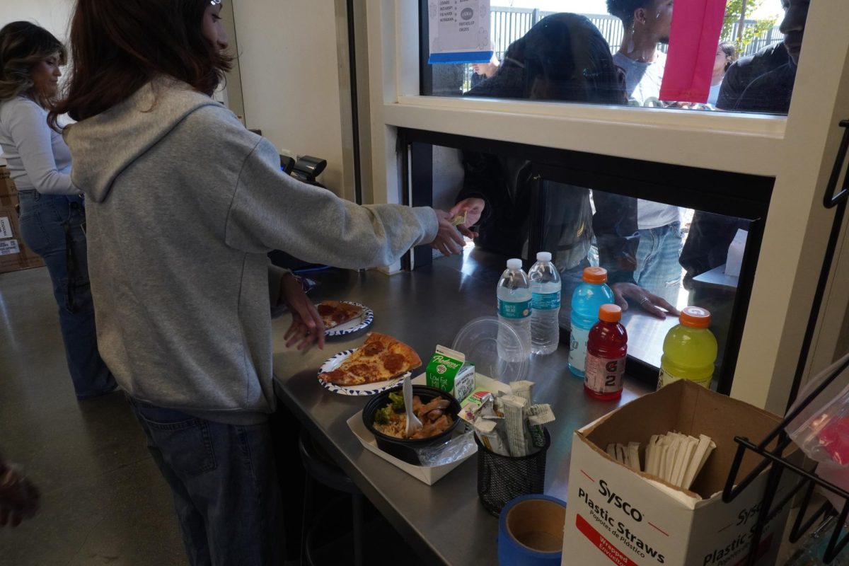 Senior Haley Ramos serves a customer a slice of hot pizza during the lunch period.